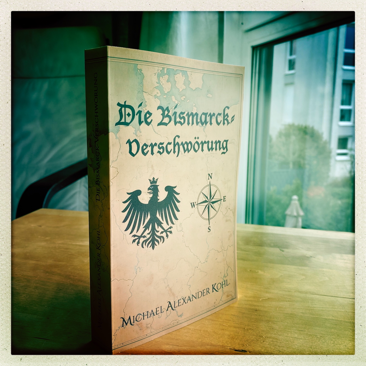 Gedrucktes Exemplar des Romans »Die Bismarck-Verschwörung« von Michael Alexander Kohl auf einem Holztisch.